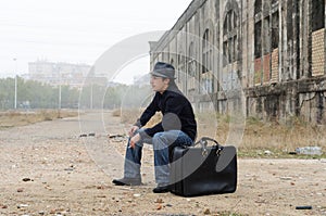Man dressed in black with hat sitting smoking