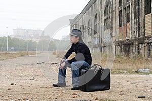 Man dressed in black with hat sitting smoking photo