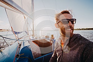 Man dressed in casual wear and sunglasses on a yacht. Happy adult bearded yachtsman close-up portrait. Handsome sailor