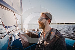 Man dressed in casual wear and sunglasses on a yacht. Happy adult bearded yachtsman close-up portrait. Handsome sailor