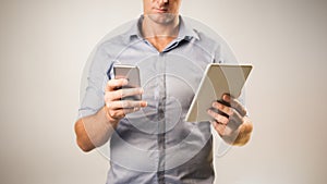 Man dressed casually in collared shirt using a tablet and phone