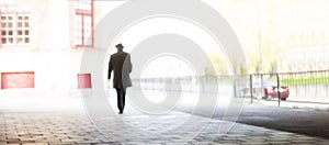 man dressed in hat walking on sidewalk in city
