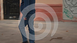man dressed in jeans and sweater walking on sidewalk, lower body. slowmotion, tracking shot