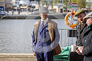 Man dressed in 1940s vintage dockland superviser costume with moustache and flat cap at Bristol Harbourside, Bristol, UK