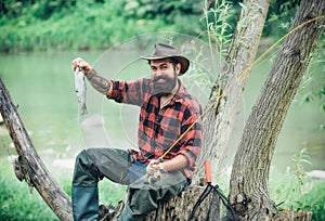 Man dressed in shirt fishing with rod and fish on the lake. Weekend. Master baiter. Male hobby. Hobby and recreation