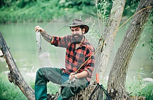 Man dressed in shirt fishing with rod and fish on the lake. Weekend. Master baiter. Male hobby. Hobby and recreation