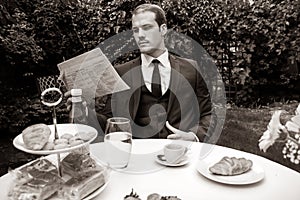 Man dressed in suit drinks esperesso at a cafe table