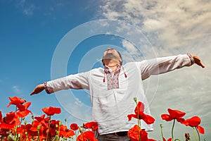 Man dressed in ukrainian embroidered costume on the red poppies field