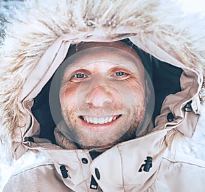 Man dressed in Warm Hooded Casual Parka Jacket Outerwear walking in snowy forest cheerful smiling face portrait. Outdoor time and