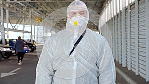 Man dressed white protective overalls walk parking. Disinfectant walking with antiviral liquid tank looking