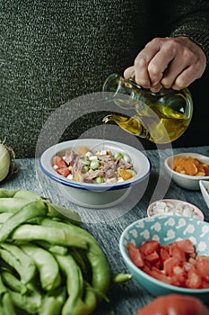 man dressing a broad bean salad with olive oil