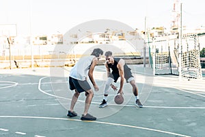 Man dribbling a friend while playing basketball outdoors