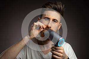 A man dries his beard with a hair dryer