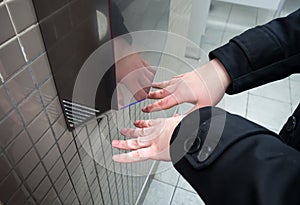 Man dries wet hands with an electric hand dryers photo