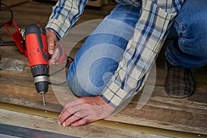 man with a drill installing floor thresholds, drill a hole in the threshold for installation, the master makes the floor