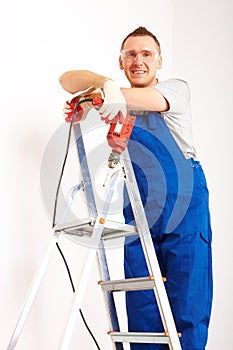 Man with drill standing on ladder