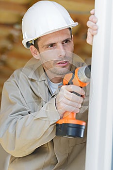 Man drilling hole in window frame
