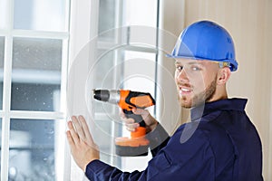 Man drilling hole in window frame