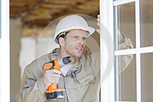 Man drilling hole in window frame