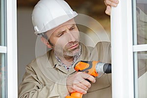 man drilling hole in window frame