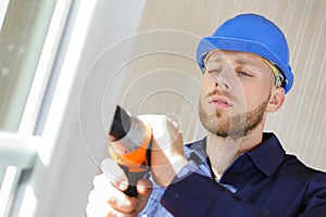 man drilling hole in window frame