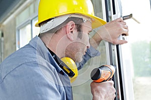 man drilling hole in window frame