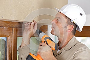 man drilling hole in window frame