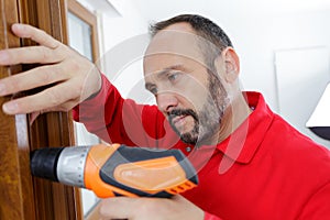 man drilling hole in window frame