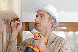 man drilling hole in window frame