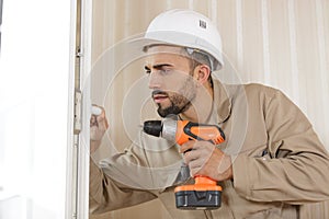 man drilling hole in window frame