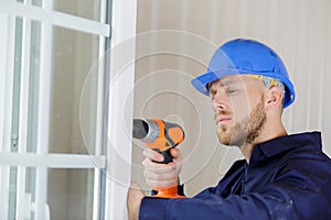 Man drilling hole in window frame