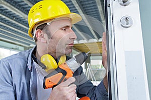 man drilling hole in window frame