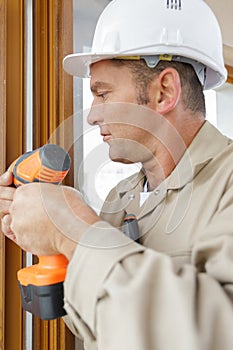 man drilling hole in window frame