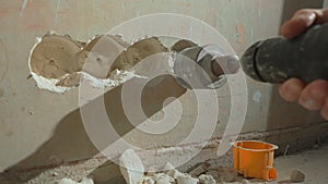 Man drilling round hole in concrete wall for socket. Builder drills hole with electric drill or perforator. Concept of