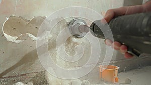 Man drilling round hole in concrete wall for socket. Builder drills hole with rotating electric drill or perforator