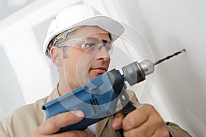 man drilling wall with drill perforator
