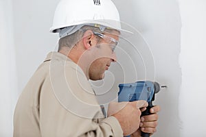 man drilling wall with drill perforator