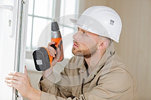 man drilling window frame