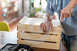 Man drilling wooden crate with power tool at home