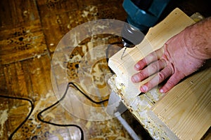A man drills a hole in a wooden board