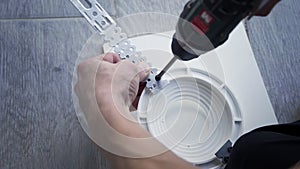 A man drills a metal surface with a drill, close-up.