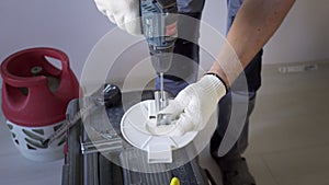 A man drills a metal surface with a drill, close-up.