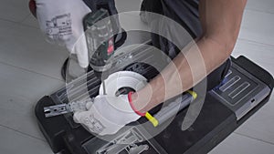 A man drills a metal surface with a drill, close-up.