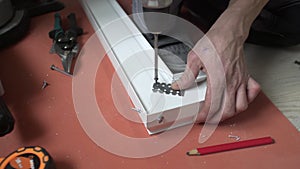 A man drills a metal surface with a drill, close-up.