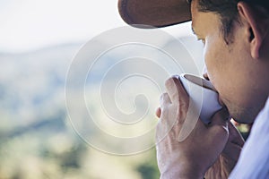 Man drink hot tea with green hill background
