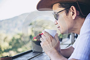 Man drink hot tea with green hill background