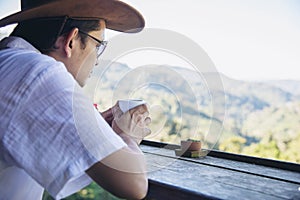 Man drink hot tea with green hill background