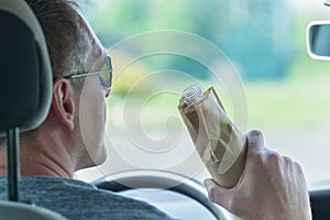 Man drinking alcohol while driving a car