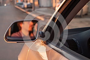 Man drinking alcohol while driving in his car on sunset. Reflection in mirror