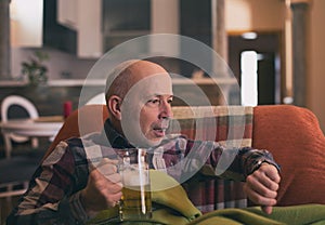 Man drinking beer at home and looking at clock